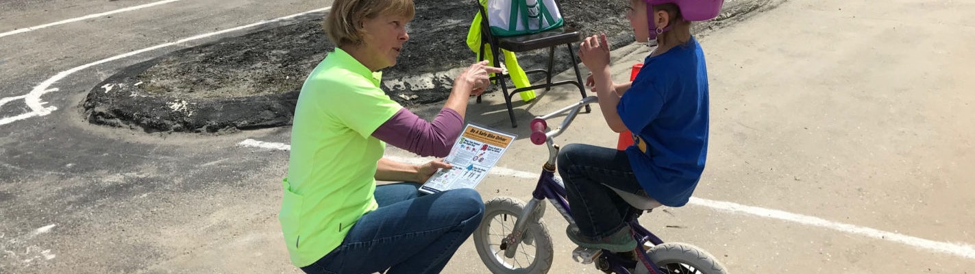 An instructor chats with a student at a bike rodeo